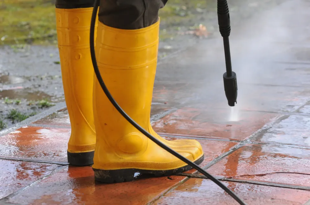 personne-portant-bottes-caoutchouc-jaune-buse-eau-haute-pression-nettoyant-salete-dans-carreaux